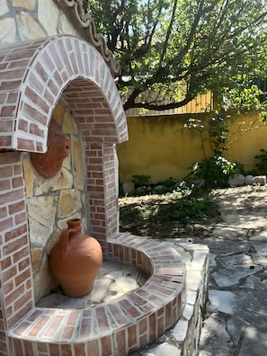 Une structure en briques contenant un pot en terre cuite à l’intérieur.
