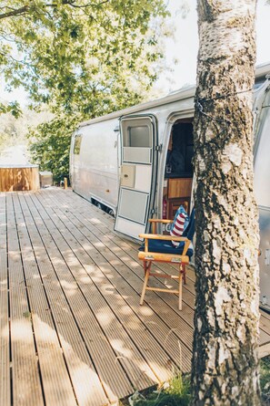A wooden deck with a bench and a tree.