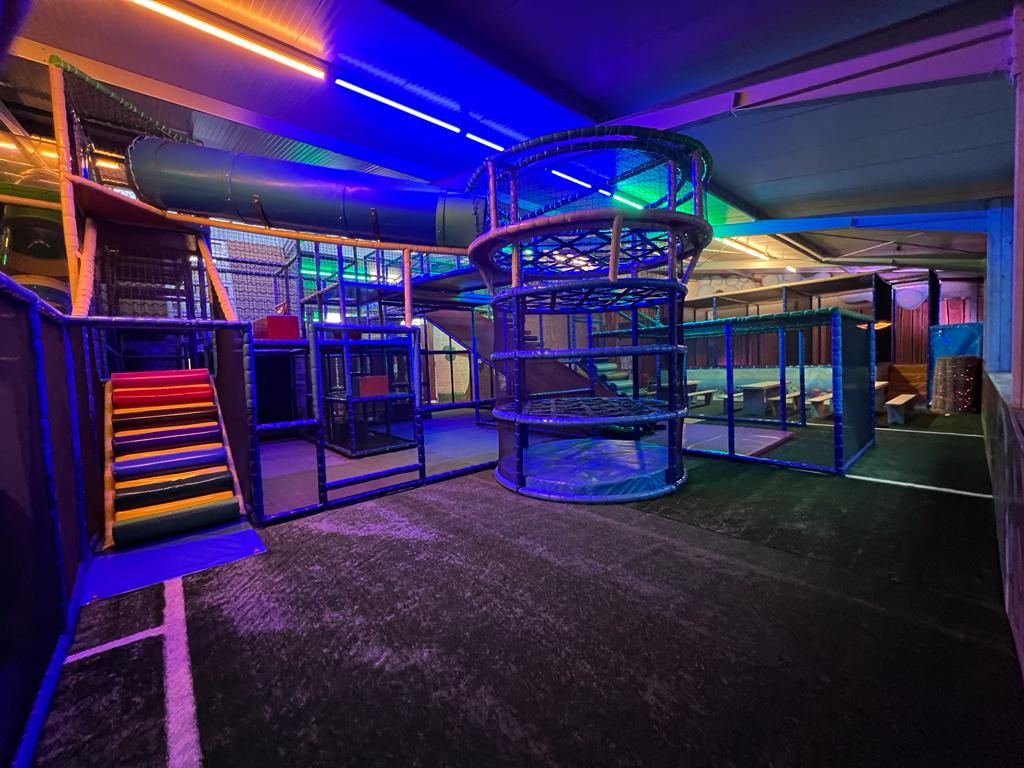 Ein Spielbereich mit einer Spirale, einer mehrstöckigen Kletterlandschaft und einer bunten Treppe.