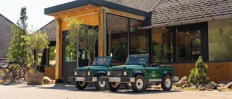 Two green Defender vehicles parked in front of a building with a covered patio area.