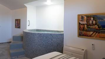 A hotel room with a bed, a painting, a tiled bathroom, and a staircase leading to a balcony.