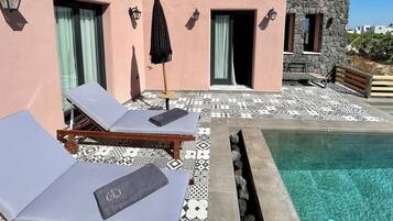 A pool area with lounge chairs and a stone building in the background.