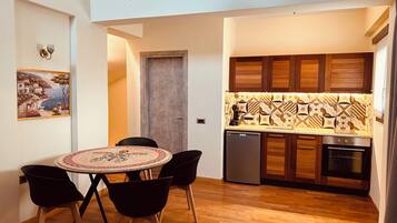A compact kitchen with wooden cabinets, a tiled backsplash, and a dining area with a round table and chairs.