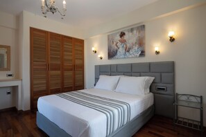A bedroom with a bed, a headboard, a painting, a wardrobe, and a chandelier.