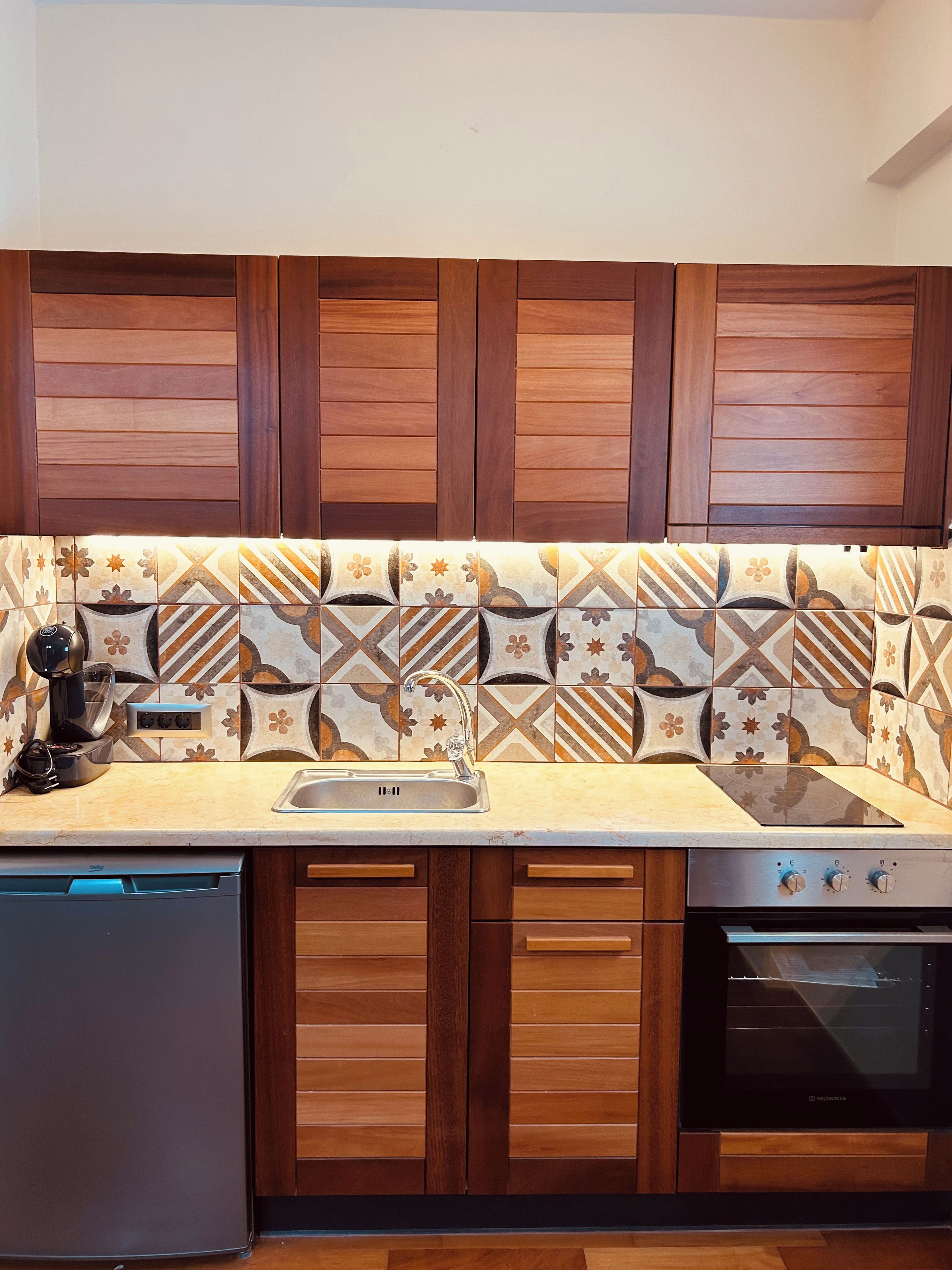 A kitchen with wooden cabinets, a patterned backsplash, a built-in dishwasher, and a stove.