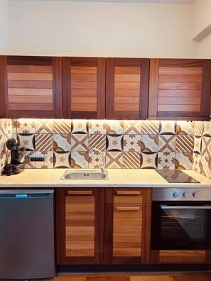 A kitchen with wooden cabinets, a patterned backsplash, a built-in dishwasher, and a stove.