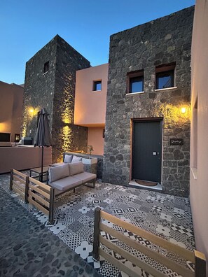 A courtyard with a stone wall, a sofa, a bench, and a door.