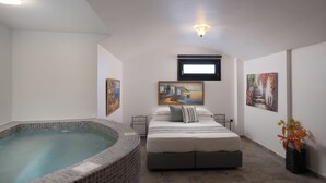 A bedroom with a bed, a painting, a window, and a hot tub. - Where luxury meets the magic of Santorini, with a private pool and private spa! (Kamari)