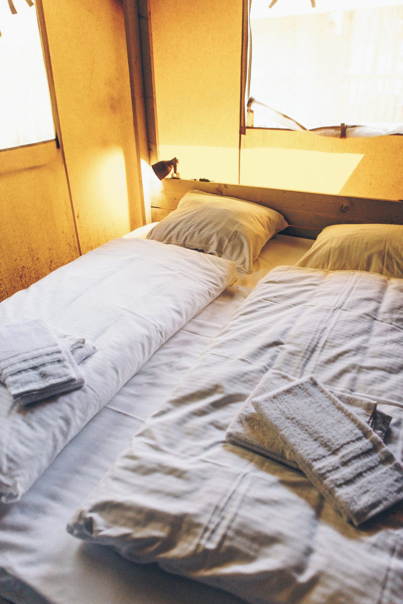 Un lit simple avec du linge de lit blanc et une serviette pliée.