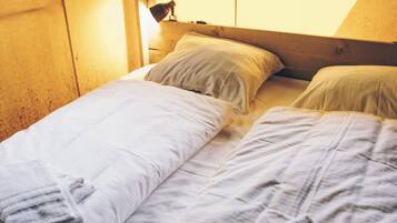 Un lit simple avec du linge de lit blanc et une serviette pliée.