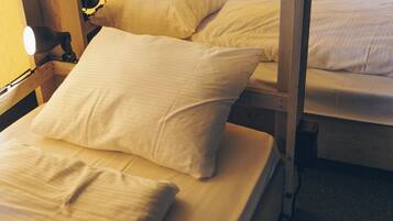 Uma cama beliche com duas almofadas e um abajur.