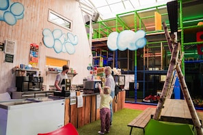A children's play area with a climbing structure, a play table, and a counter with a menu.