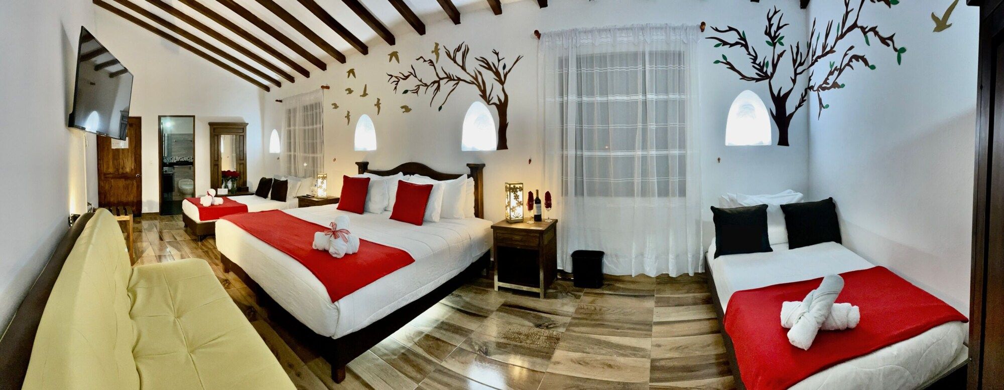 A hotel room with two beds, a sofa, and a mirror.