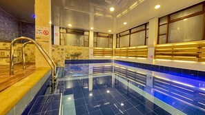 A swimming pool with a tiled floor, a metal ladder, and a wooden deck. - Hotel VDL Colonial by Prima Collection (Villa de Leyva)