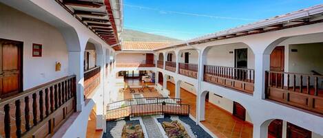 A courtyard with multiple balconies, a central seating area, and a tiled floor.