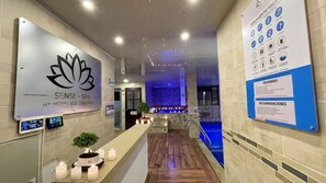Un espace d’accueil d’hôtel avec un panneau indiquant « SENSE – SPA » et un écran numérique.