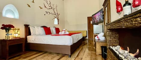 Habitación de hotel con cama, televisión, chimenea y un mural de un árbol en la pared.