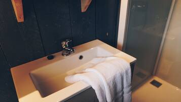 Une salle de bain avec un lavabo, une serviette et un espace douche.