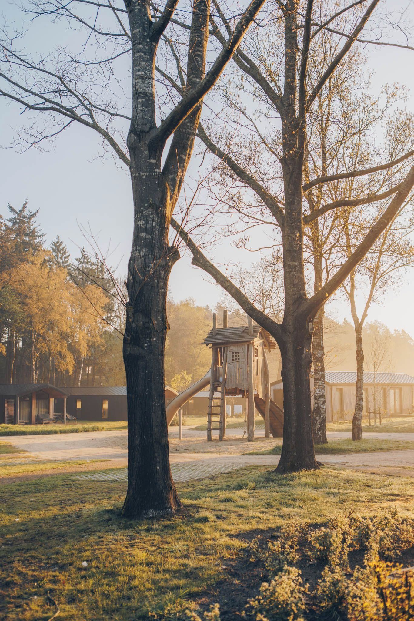 Un parc avec une aire de jeux et un bâtiment doté d’un toit en pente.