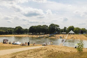 Un parque junto al lago con zonas de arena, una rampa para embarcaciones y un pequeño edificio.