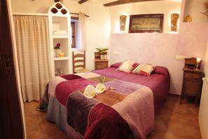 Ein Schlafzimmer mit einem großen Bett, einem hölzernen Kopfteil, einem Nachttisch, einem Regal mit Dekoration und einem Gemälde an der Wand.