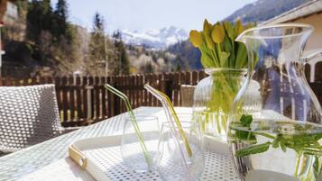 A table with a pitcher, glasses, and a tray, set outdoors with a mountain view.