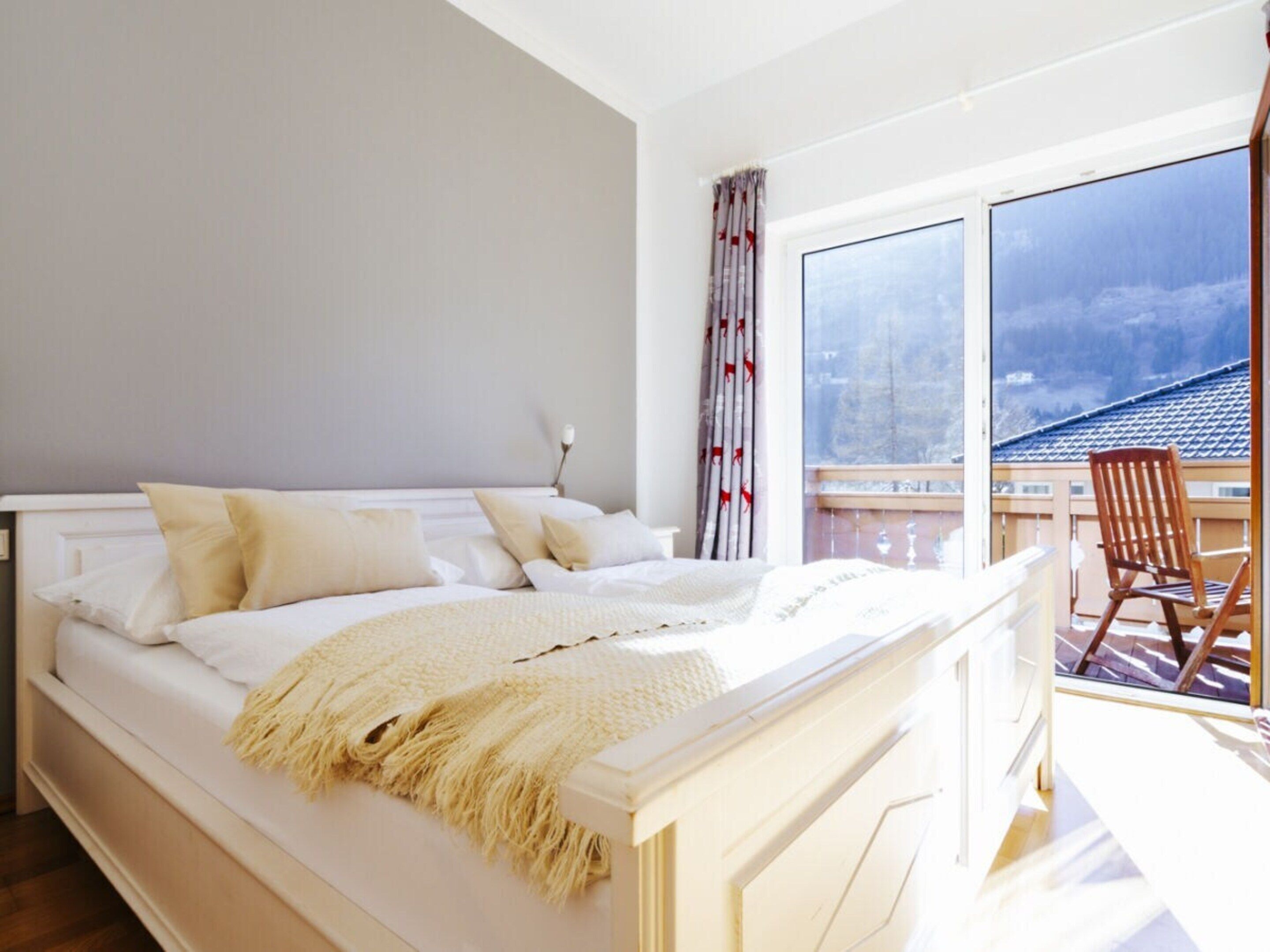 A bedroom with a large bed, a window, and a view of a balcony.