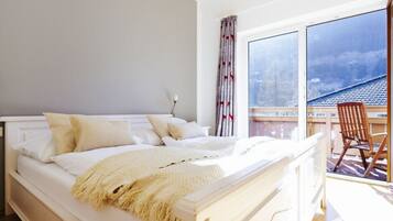 A bedroom with a large bed, a window, and a view of a balcony.