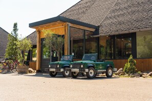 Two green Defender vehicles parked in front of a building with a covered patio area.