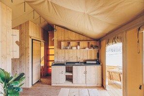 Una cabana de fusta compacta amb una cuina americana, zona de menjador i una finestra gran.