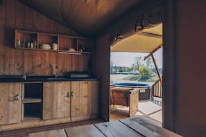 Un interior de fusta amb una zona de cuina, un balcó de fusta i una banyera hidromassatge a l'exterior.
