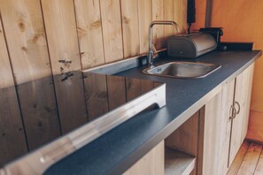 A kitchen with a wooden wall, a stainless steel sink, and a toaster.