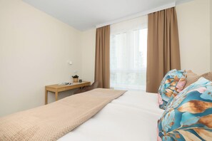A bedroom with a bed, a desk, and a window with curtains. - Cracow | Łaszkiewicza 8B | Comfortable Apartment | Parking (Kraków)