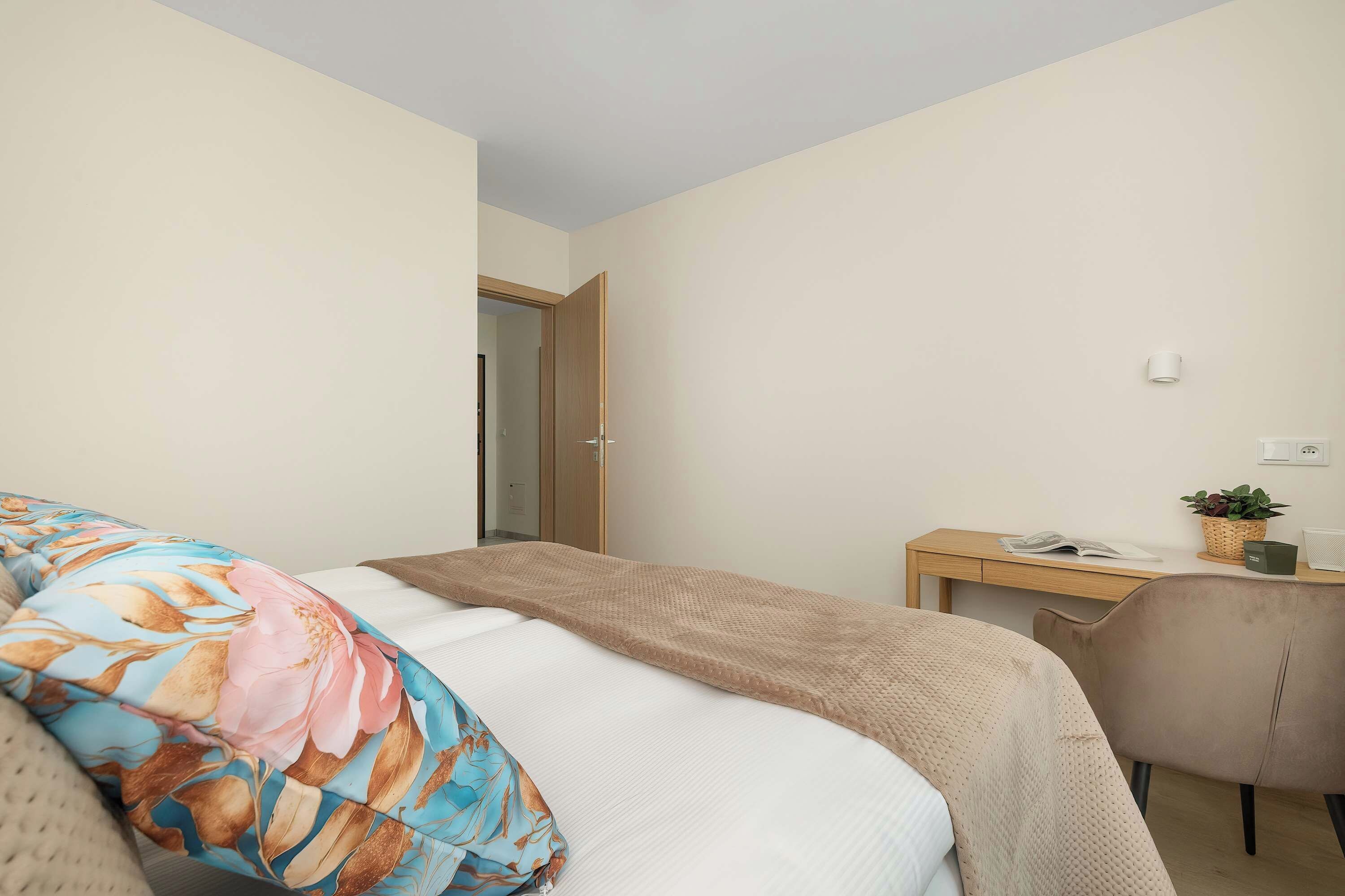 A bedroom with a bed, a desk, and a chair.