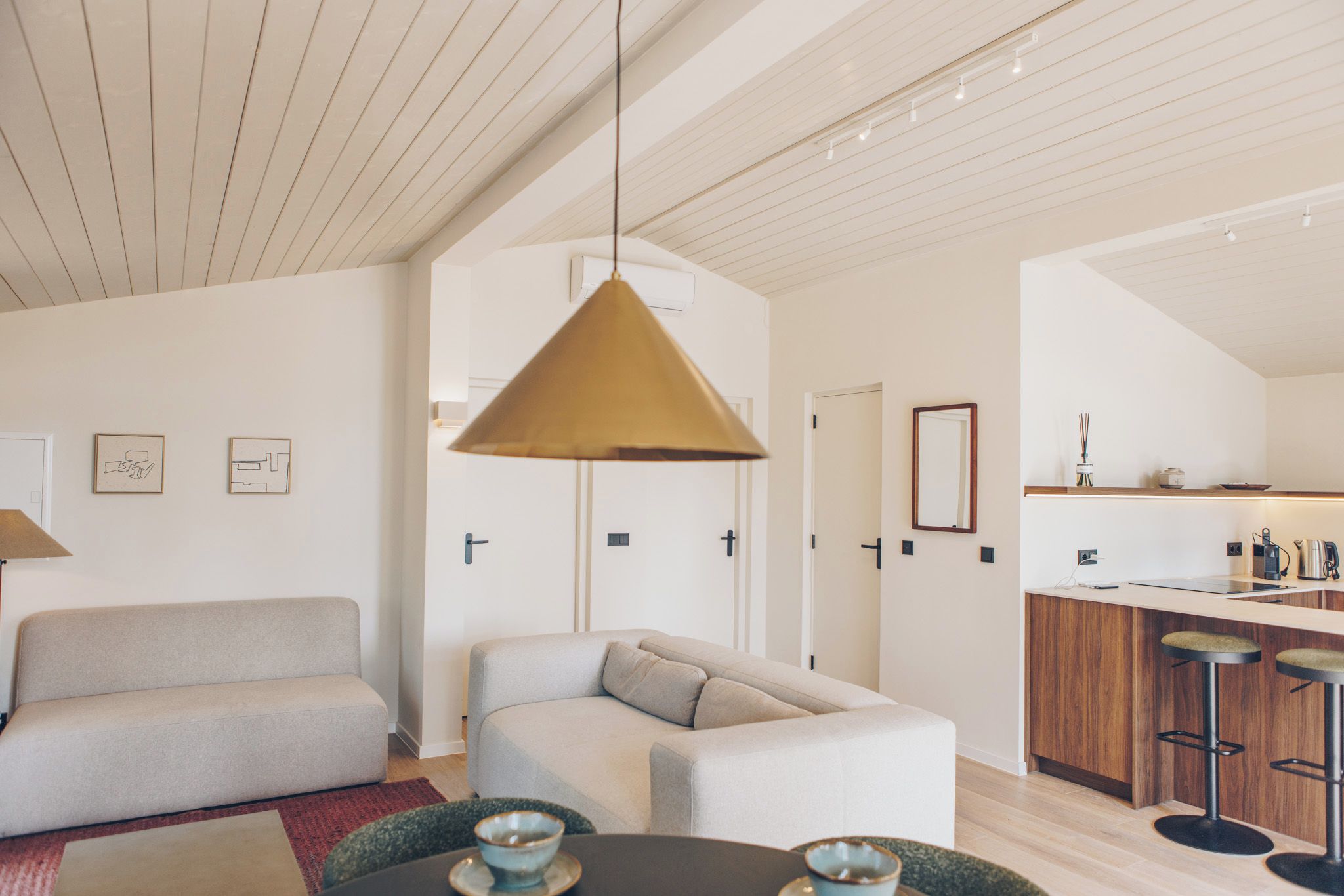 A modern living room with a sofa, a coffee table, and a hanging pendant light.