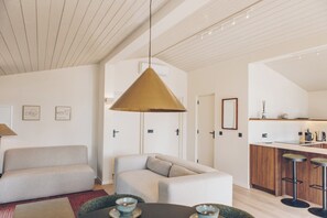 A modern living room with a sofa, a coffee table, and a hanging pendant light.