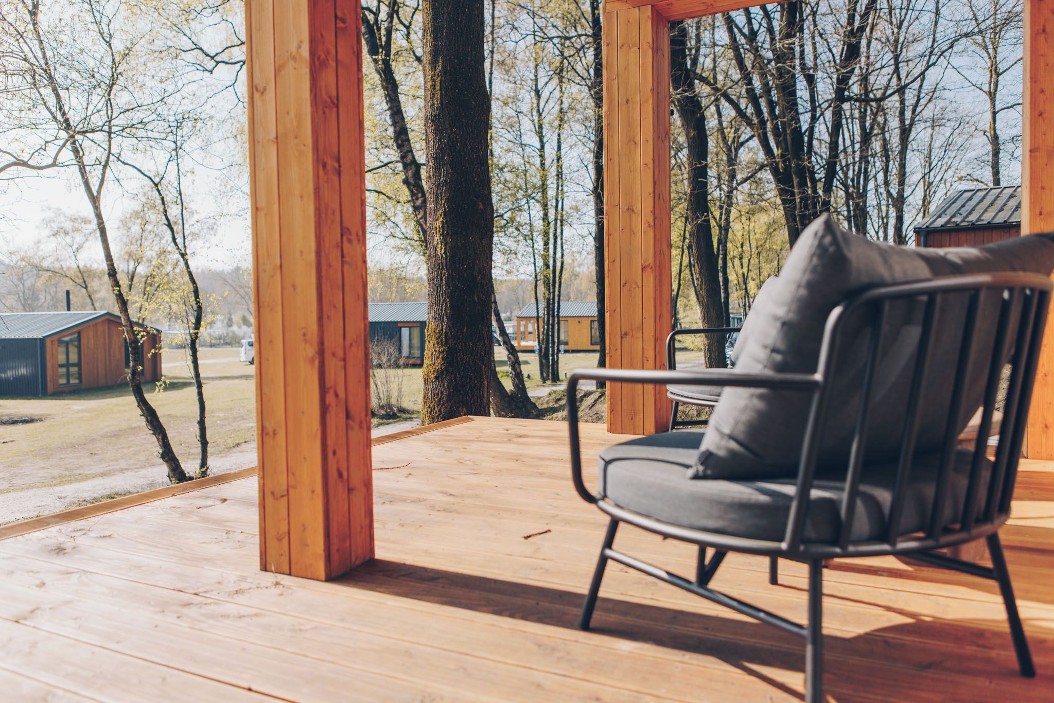 Une terrasse en bois avec une chaise en métal et une vue sur un paysage rural.