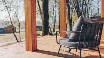 Une terrasse en bois avec une chaise en métal et une vue sur un paysage rural.