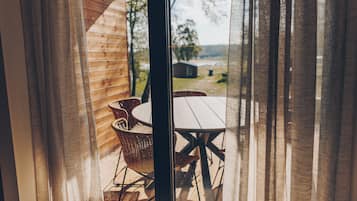 A wooden cabin with a dining area featuring wicker chairs and a table.