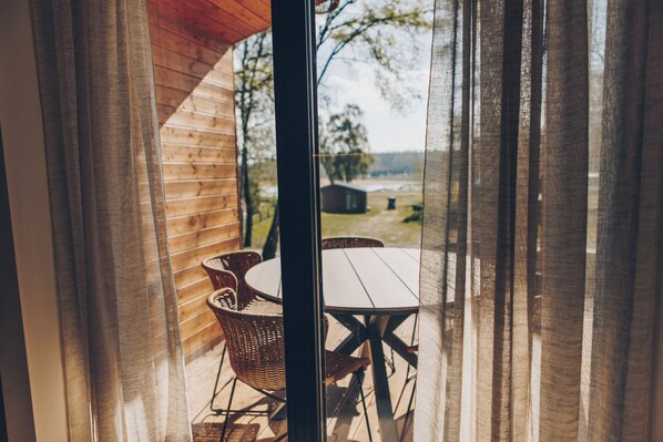 A wooden cabin with a dining area featuring wicker chairs and a table.