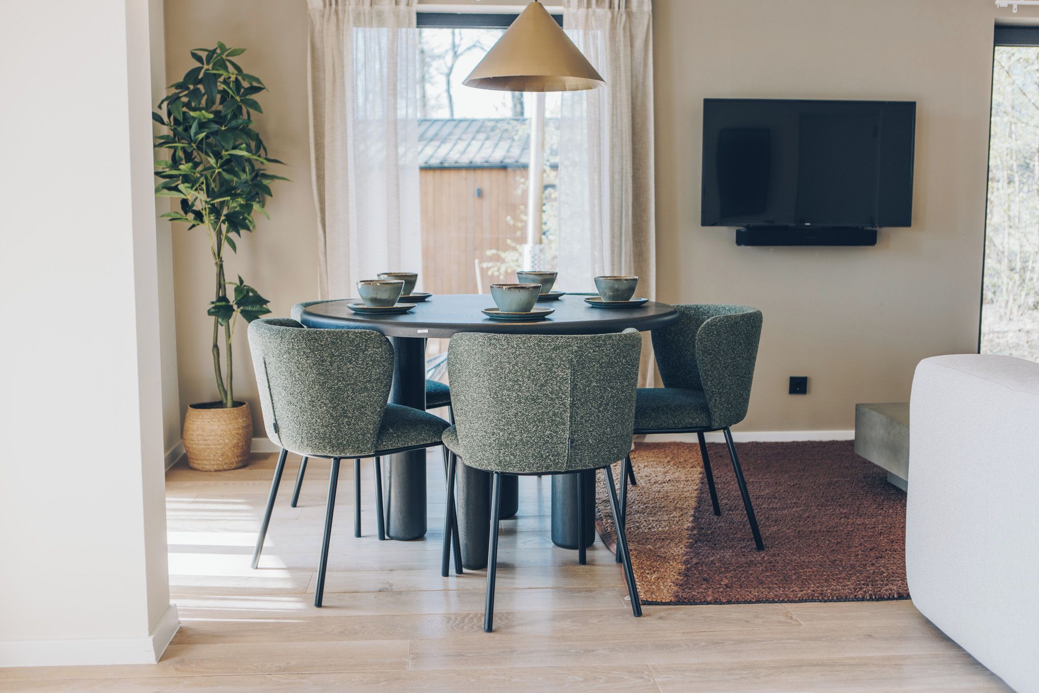 Un coin repas avec une table ronde, quatre chaises et une plante en pot.