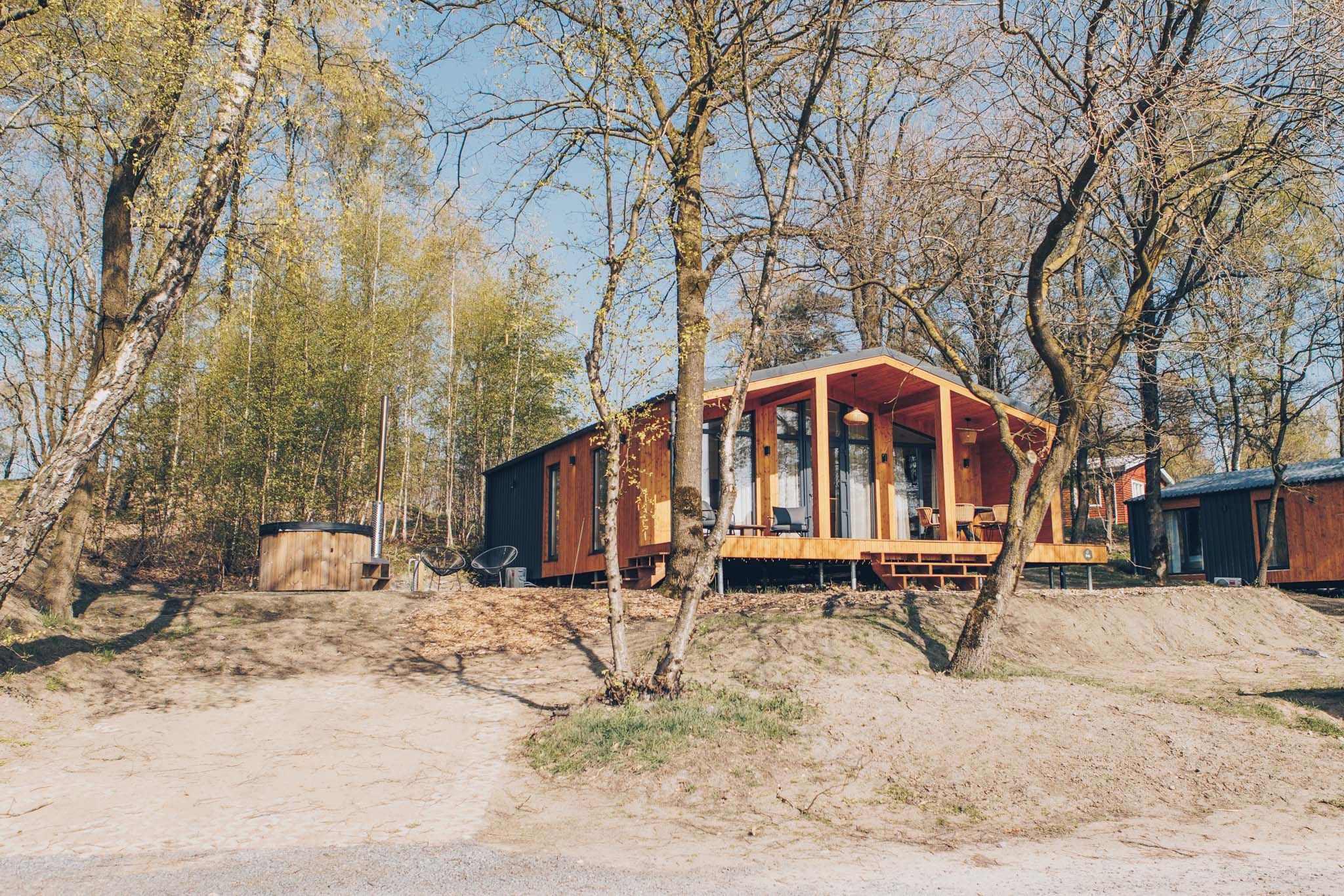 Une cabane en bois avec un porche, entourée d’arbres.