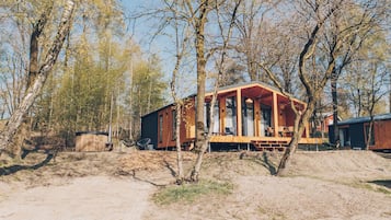 Une cabane en bois avec un porche, entourée d’arbres.