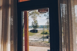 A view through a doorway with a wooden structure and a fenced area with trees.