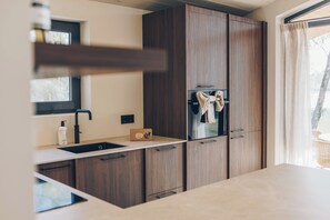 A modern kitchen with wooden cabinets, a built-in oven, and a window with curtains.