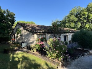 A rustic stone house with a sloped roof, surrounded by a garden with various flowering plants. - Holiday Home 'Sautou' with Private Pool, Private Terrace and Wi-Fi (Penne-d'Agenais)