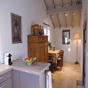 A kitchen with a wooden cabinet, a fruit bowl, a dining table with chairs, and a lamp. - Holiday Home 'Sautou' with Private Pool, Private Terrace and Wi-Fi (Penne-d'Agenais)