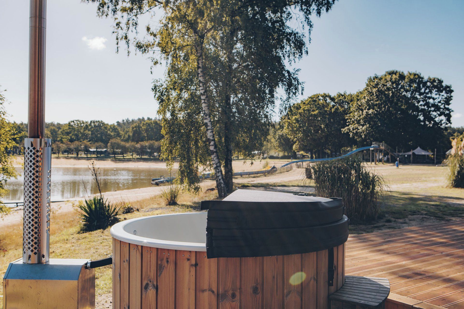 A hot tub on a wooden deck with a view of a lake and trees.