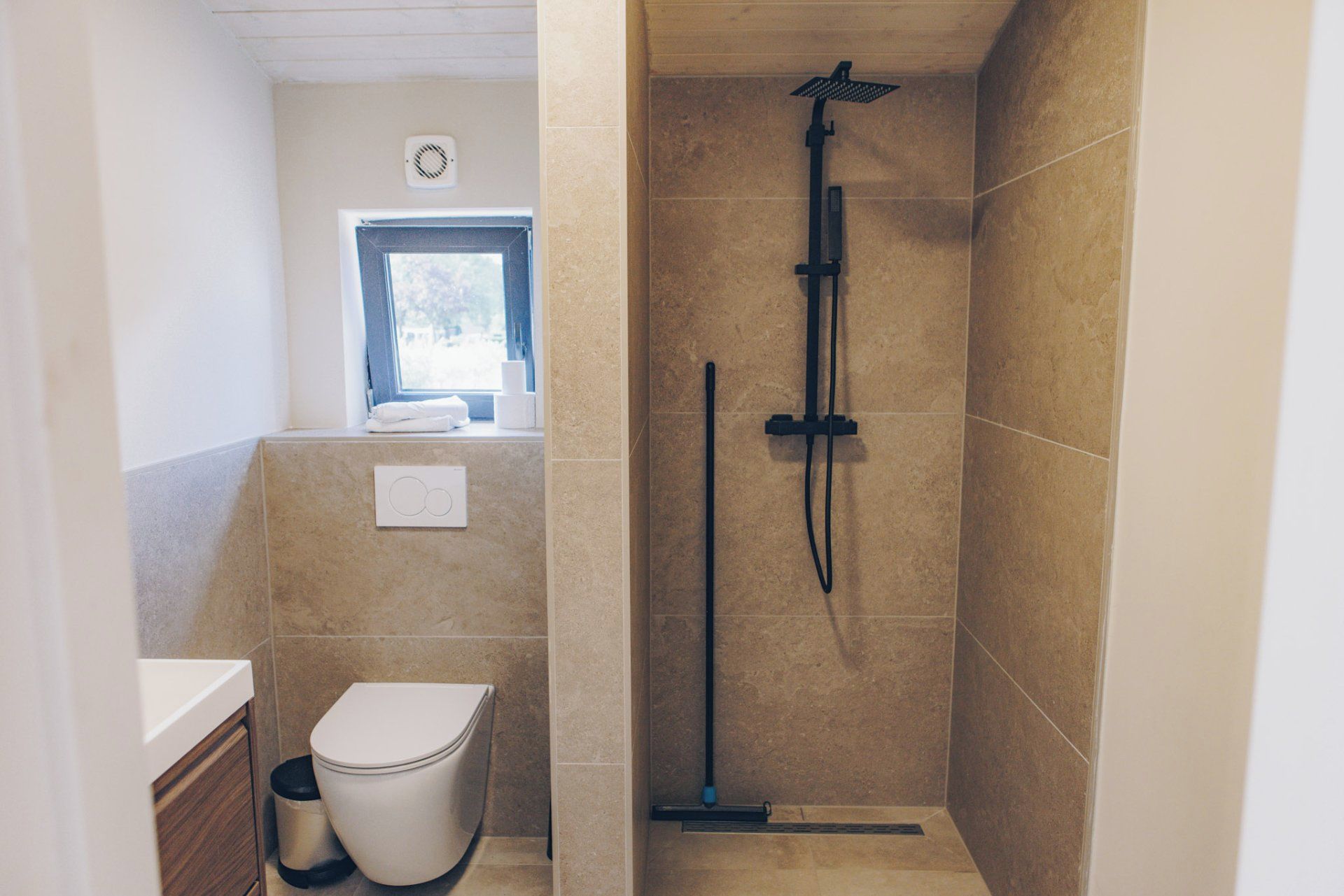 Ein Badezimmer mit Toilette, Fenster und Duschbereich.