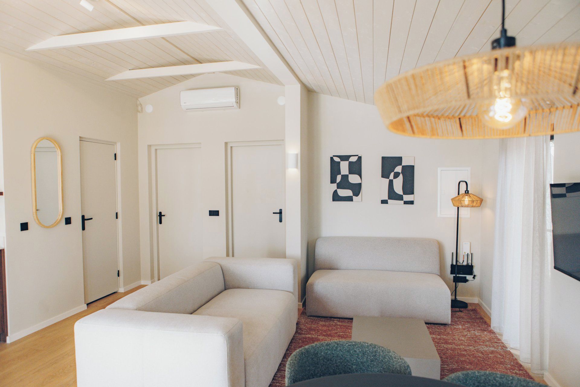 Een moderne woonkamer met een bank, een fauteuil, een lamp en kunst aan de muur.